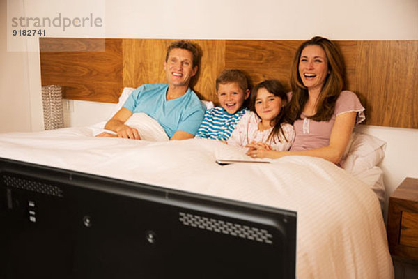 Familie beim Fernsehen im Bett