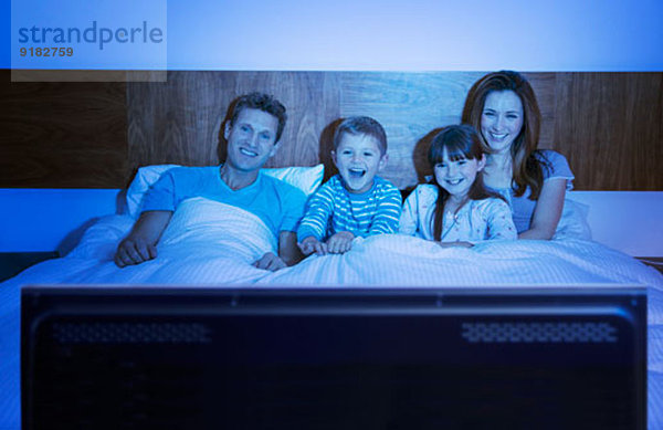 Familie beim Fernsehen im Bett