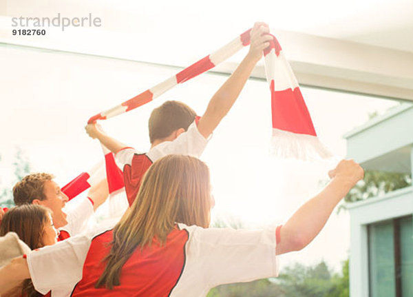 Familie im Sporttrikot jubelnd im Wohnzimmer