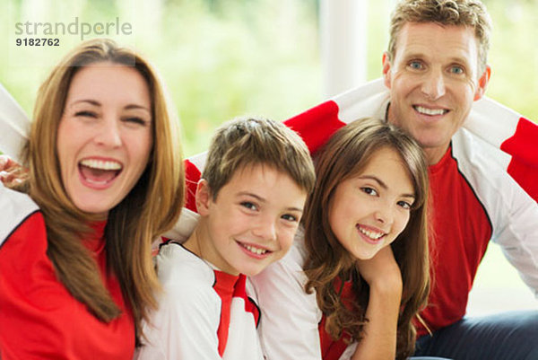 Familie im Sporttrikot jubelnd im Wohnzimmer