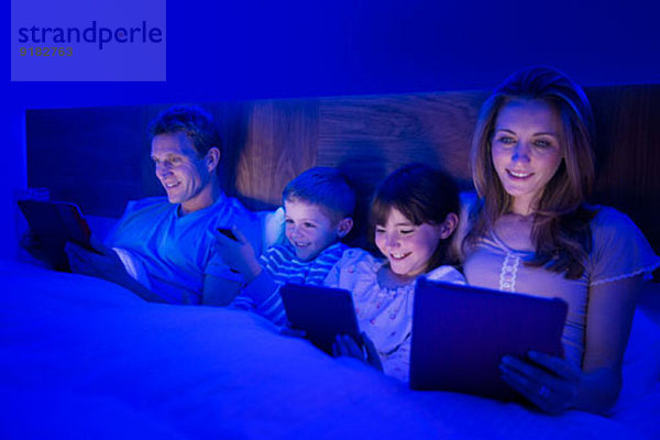 Familie mit Technik im Bett