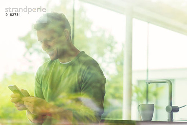 Mann mit Handy durchs Fenster gesehen