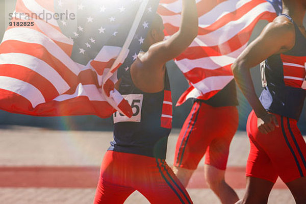 Leichtathleten mit amerikanischen Flaggen auf der Strecke