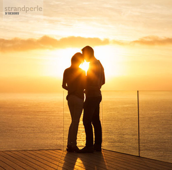Silhouette des Paares bei Sonnenuntergang über dem Meer