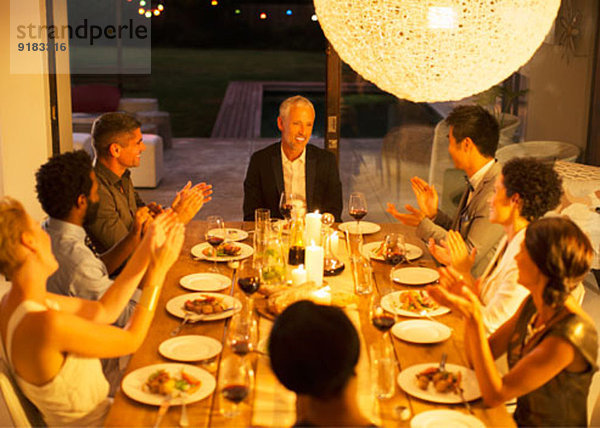 Freunde applaudieren Mann bei Dinnerparty