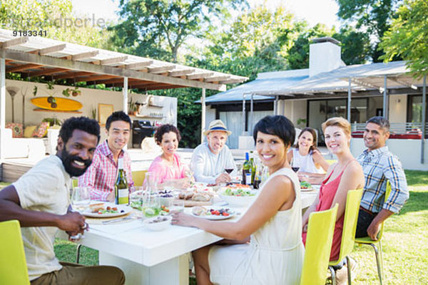 Freunde lächeln bei Tisch im Freien