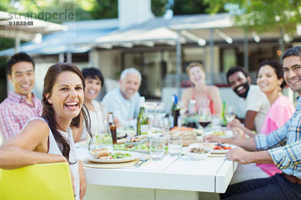 Freunde lächeln bei Tisch im Freien