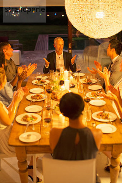 Freunde applaudieren Mann bei Dinnerparty