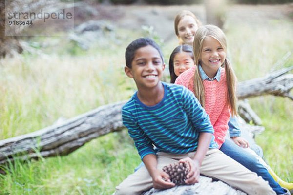 Kinder sitzen auf dem Baumstamm im Wald