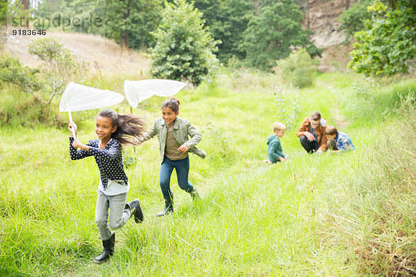 Kinder spielen mit Schmetterlingsnetzen auf dem Feldweg