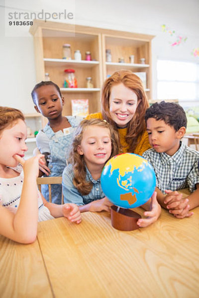 Schüler und Lehrer untersuchen den Globus im Klassenzimmer