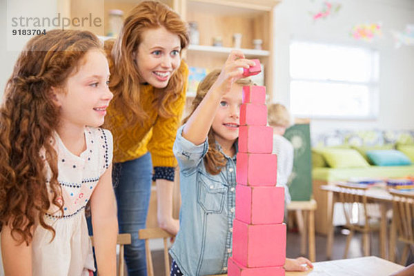 Schüler und Lehrer stapeln Blöcke im Klassenzimmer