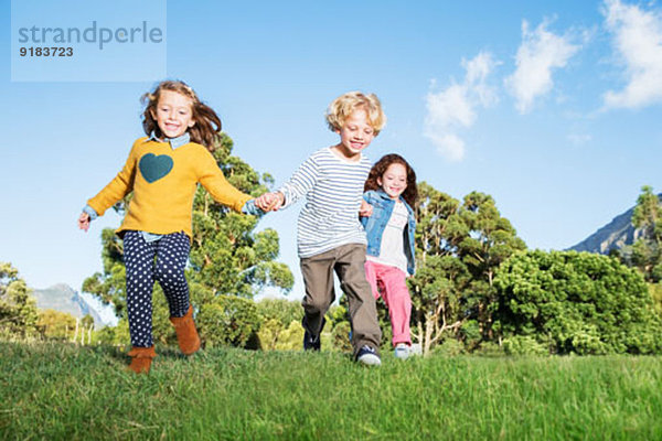 Kinder halten sich auf dem Feld an den Händen