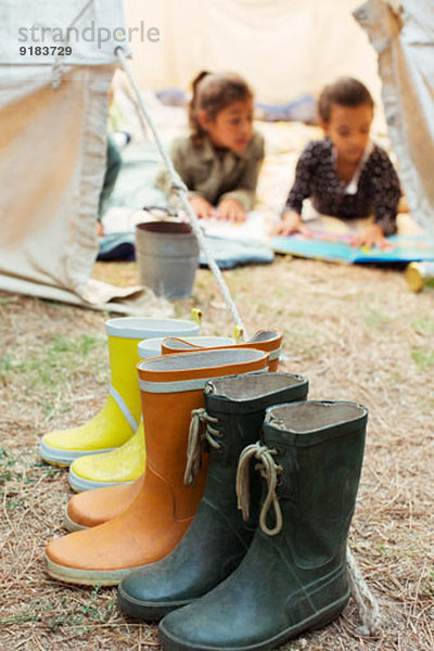 Regenstiefel vor dem Zelt auf dem Campingplatz aufgereiht