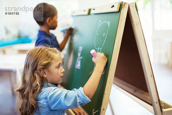 Schülerinnen und Schüler zeichnen im Klassenzimmer auf Kreidetafel