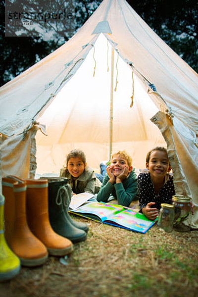 Kinder lächeln im Zelt auf dem Campingplatz