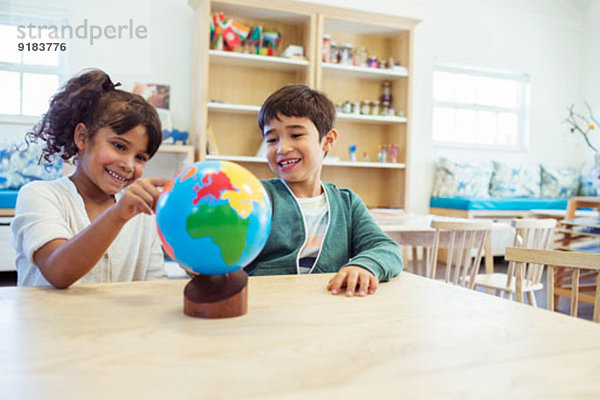 Schüler untersuchen den Globus im Klassenzimmer