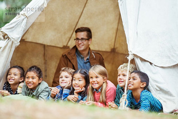 Schüler und Lehrer lächeln im Zelt auf dem Campingplatz