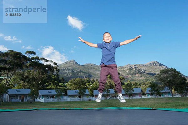 Junge springt auf Trampolin im Freien