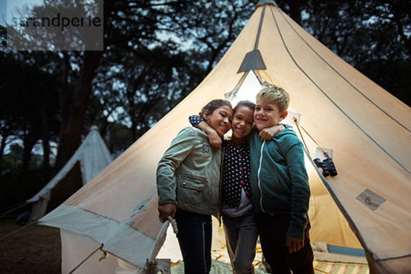 Kinder umarmen sich mit dem Tipi auf dem Campingplatz