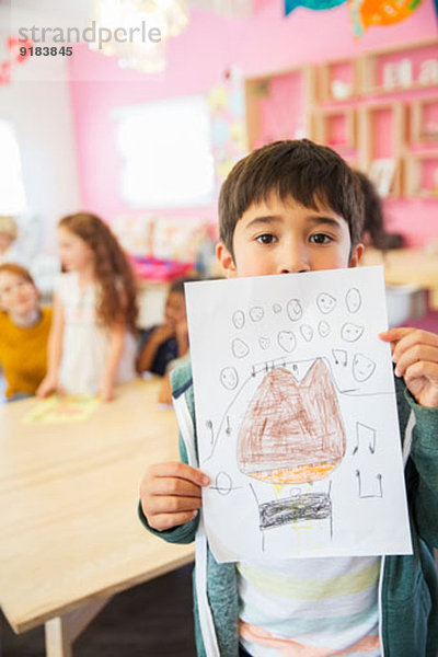 Schüler zeigt Zeichnung im Klassenzimmer