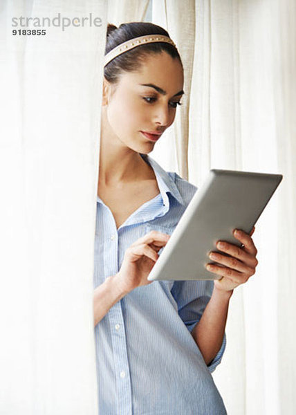 Frau mit digitalem Tablett am Fenster