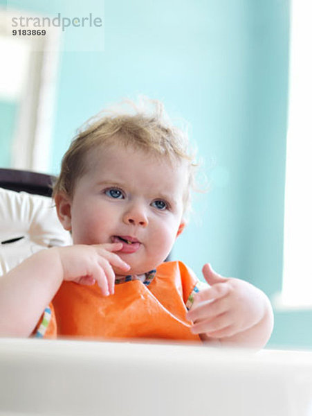 Baby Mädchen beim Essen im Hochstuhl