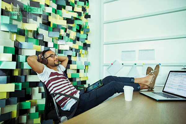 Mann entspannt am Schreibtisch im Büro