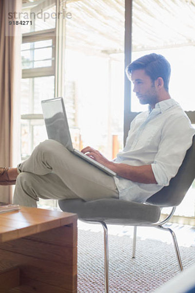 Mann mit Laptop im Wohnzimmer