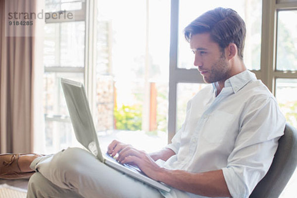 Mann mit Laptop im Wohnzimmer