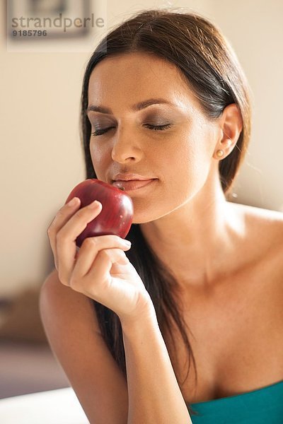 Porträt einer jungen Frau  die roten Apfel riecht