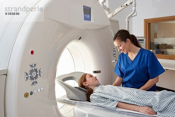 Radiografin beruhigt Mädchen  die in den CT-Scanner geht.