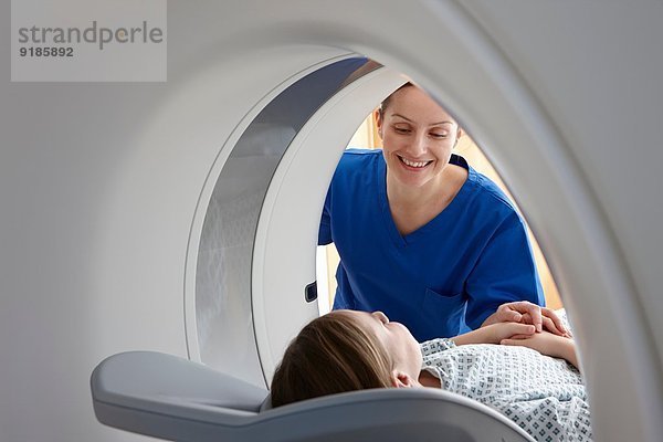 Radiografin lächelt Mädchen im CT-Scanner an