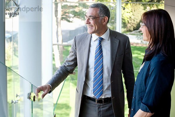 Geschäftsmann und Frau mit Blick aus dem Bürogebäude