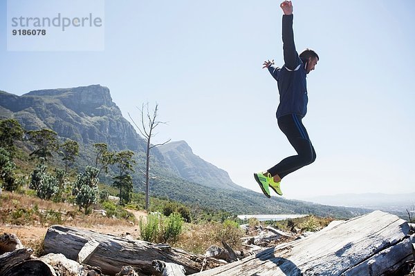 Männlicher Jogger beim Springen in der Luft