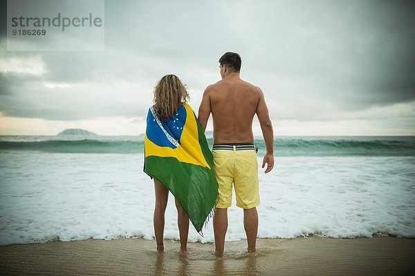 Junges Paar  Frau in brasilianischer Flagge  Ipanema Beach  Rio de Janeiro  Brasilien