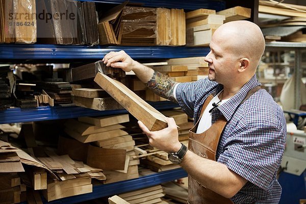 Gitarrenbauer bei der Auswahl des Holzklotzes in der Werkstatt