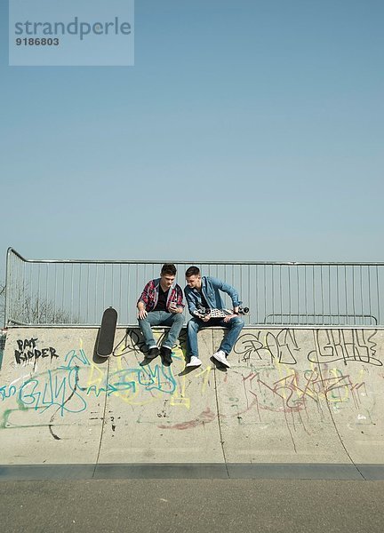 Junge Männer im Skatepark mit Smartphone
