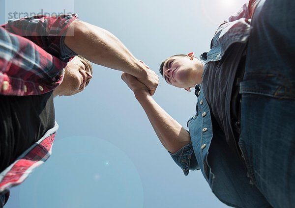 Blick von unten auf junge Männer  Händeschütteln