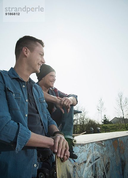 Junge Männer sitzen zusammen im Skatepark