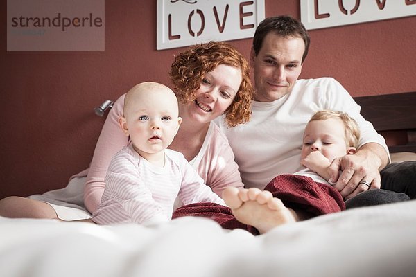 Porträt eines erwachsenen Paares mit Sohn und Tochter im Bett