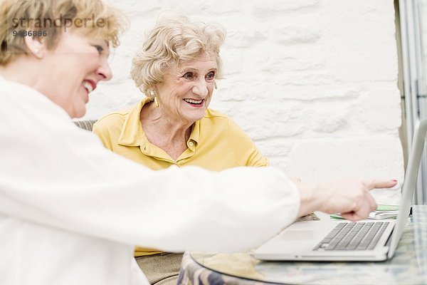 Seniorin und Tochter beim Blick auf den Laptop