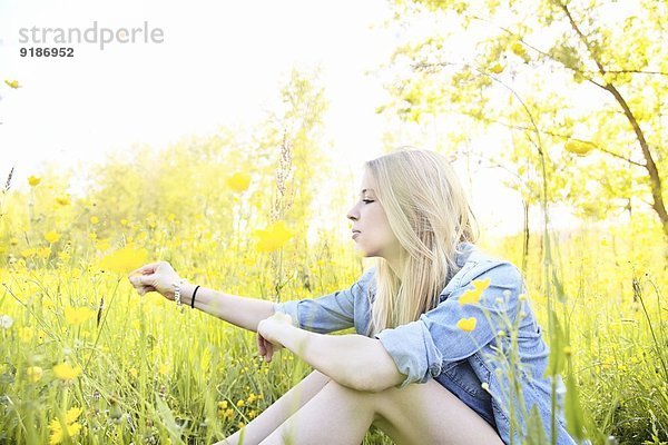 Junge Frau im Feld sitzend mit Wildblumen