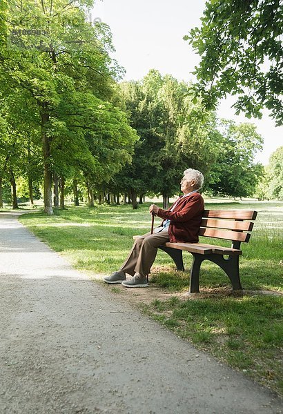 Seniorin auf Parkbank im Park sitzend