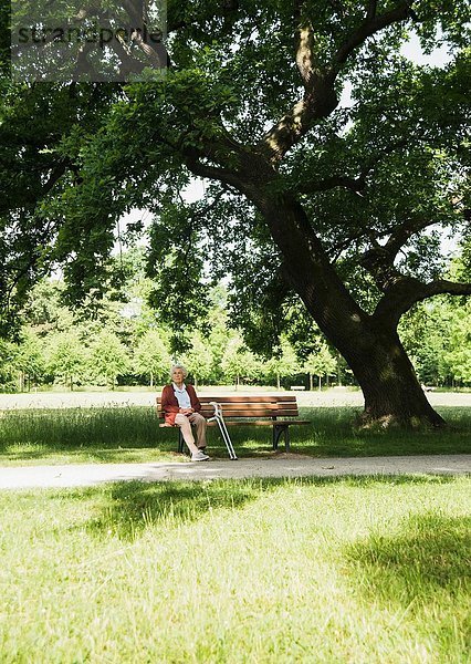 Seniorin auf Parkbank im Park sitzend