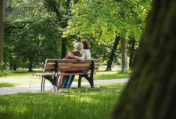 Seniorin sitzend auf Parkbank mit Enkelin