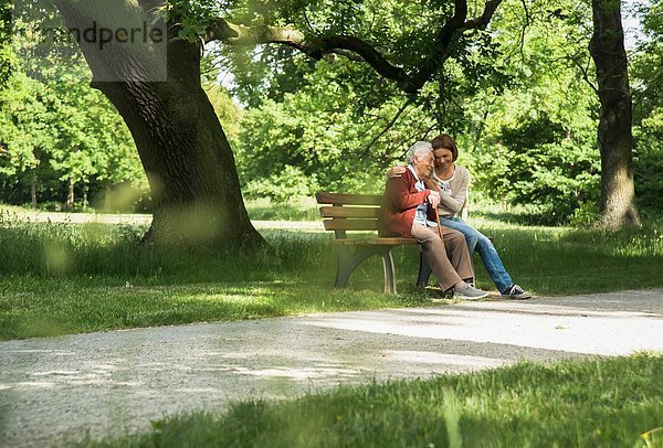 Seniorin sitzend auf Parkbank mit Enkelin