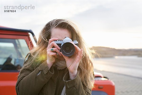 Mittlere erwachsene Frau beim Fotografieren mit SLR auf dem Küstenparkplatz