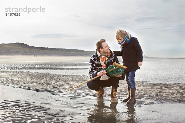 Mittlerer Erwachsener Mann und Sohn mit Fischernetz am Strand  Bloemendaal aan Zee  Niederlande