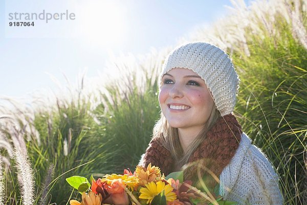 Bildnis einer jungen Frau mit Blumenstrauß im langen Gras